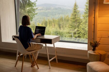 Woman works on laptop remotely in house on nature